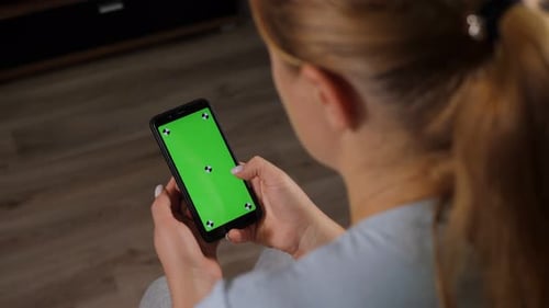 Closeup of Woman's Hand Browsing Smartphone with Green Screen at Home