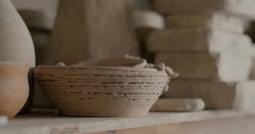Closeup of Beautiful Handmade Dishes and Pots Made of Clay on Wooden Shelf in Pottery Workshop