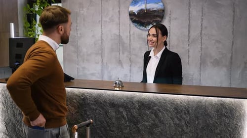 Hotel Receptionist Welcoming Guest During Check in