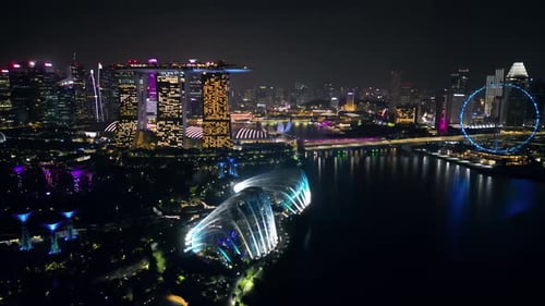 Aerial drone view of Marina Bay in Singapore at night showing Marina Bay Sands, the Singapore Flyer