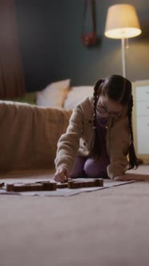 Niña inteligente ensamblando un rompecabezas de madera en el piso de una acogedora habitación
