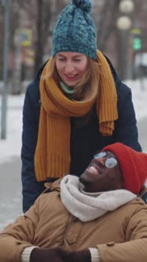 Woman Assisting Friend in Wheelchair during Winter Walk
