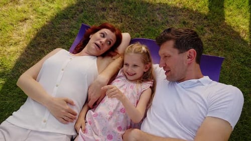 Happy Family Relaxing Together on Grassy Lawn