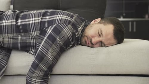 Man Sleeping Peacefully on Gray Couch Indoors