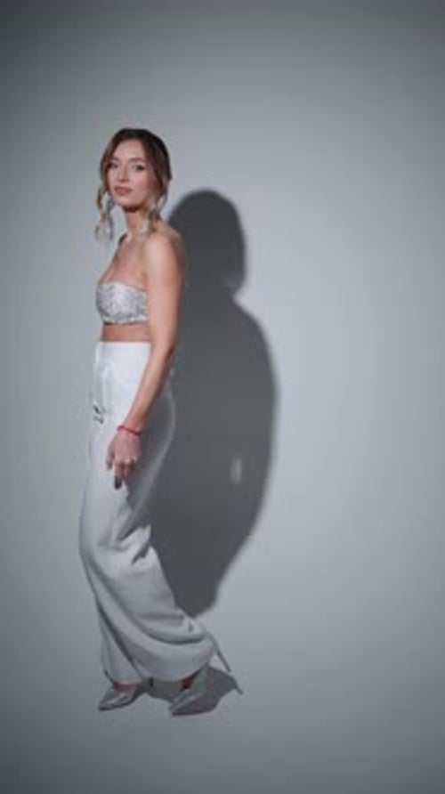 Elegant Woman in White Trouser Suit and Shiny Top High Fashion and Style Concept