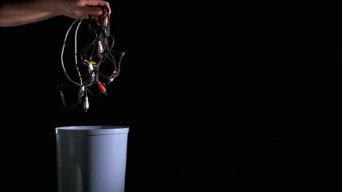 Hand Throws Wires into Trash Can at Night