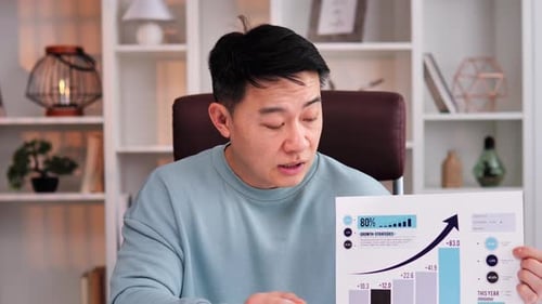 Concentrated Asian Young Man Having Business Video Chat on Laptop in Office