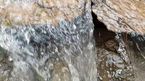 flowing waterfall from a mountain spring water stream running down huge sandstone slabs of rock with