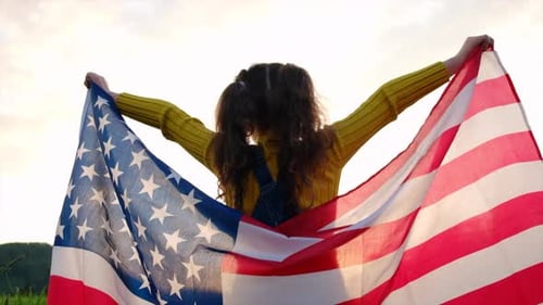 Child Raises American Flag in Sunny Meadow