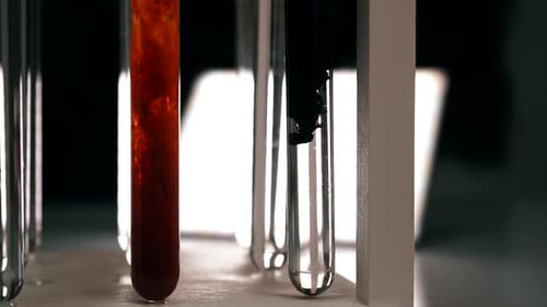 Das chemische schwarze Reagenz löst sich langsam in einem Reagenzglas mit einer klaren Flüssigkeit auf