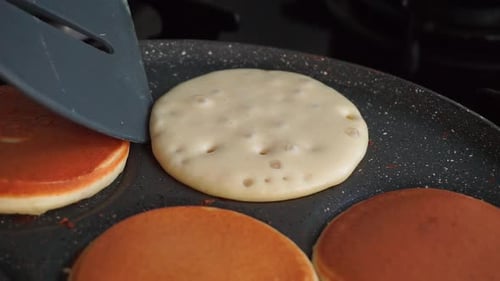 Turn the pancake cooked in the pan with a spatula