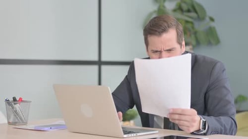 Frustrated Man at Work Reading Documents