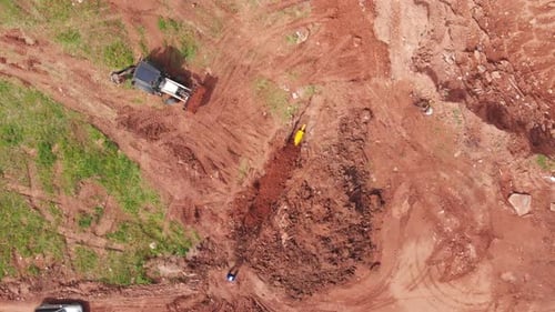 La excavadora transporta la tierra para enterrar una zanja con un tubo de metal amarillo