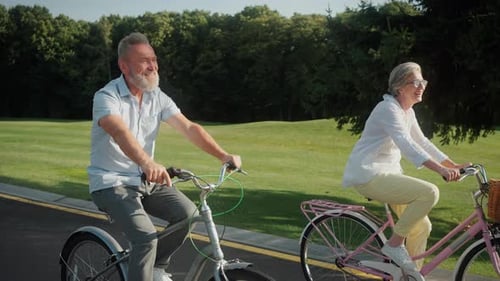 Joyful Pensioners Pedaling Vintage Bicycles at Summer Park