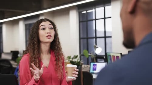 Two happy diverse creative colleagues in discussion in casual office, slow motion