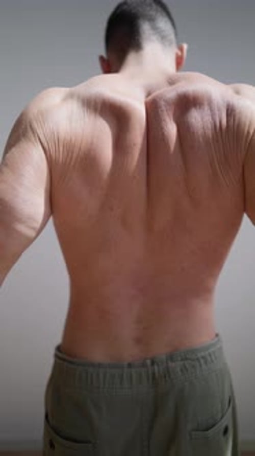 Adult Male Stretches Back Muscles Indoors