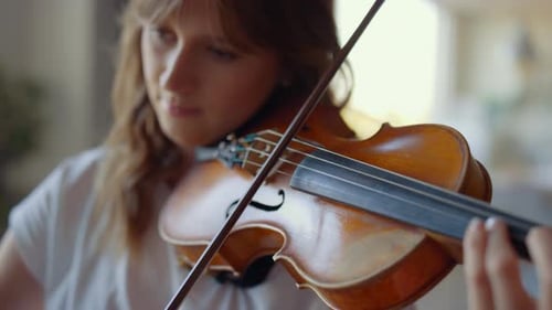 Young Woman Plays Violin Indoors in Natural Light
