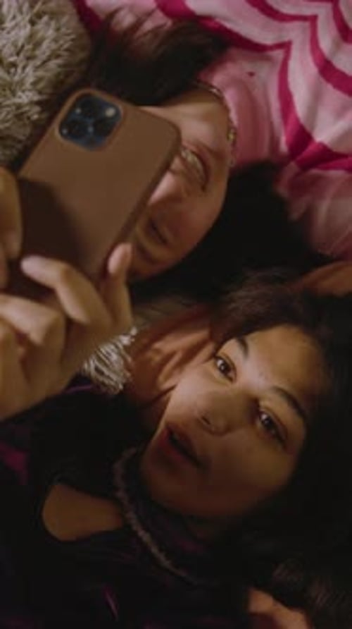 Young Women Taking Selfie Together Lying Down