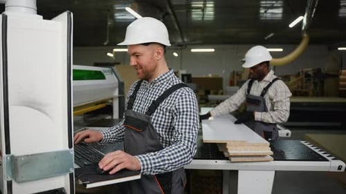 Two Workers Cutting Wood Panel Into Furniture Parts