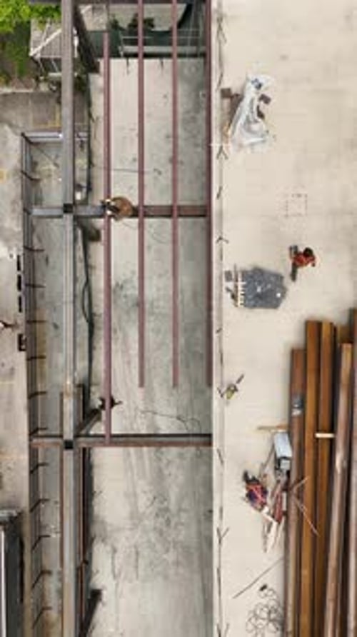 Vídeo vertical: vista aérea de constructores del área de construcción descargando vigas de metal en un comercio minorista en expansión