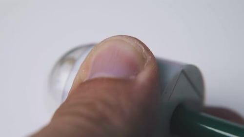Man Turns Green Pencil Holding Sharpener on Light Background