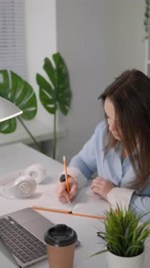 Woman Working at Desk Writing in Notebook