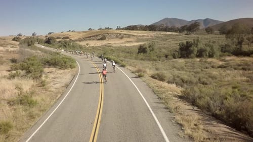 Drone View Of Bike Race On Open Road With Mountains In Background 12