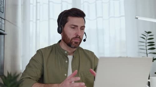 Man with Headset Talking on Laptop at Home