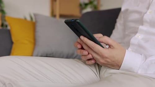 Empresario profesional que usa un teléfono inteligente móvil sentado en el sofá de su casa
