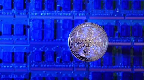 A tracking shot of Cardano ADA crypto currency coin hovering over a mining rig of computer chips.