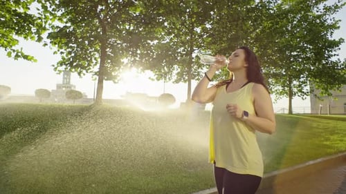 A Girl Drinks Water From a Bottle After a Morning Run