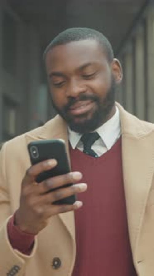 Smiling Man Checks Smartphone in Urban Setting