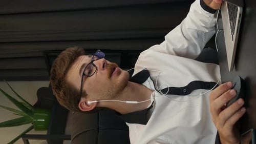 Man wearing earphones doing online video conference at work. Vertical video