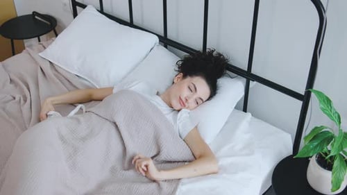Young Woman Waking up and Stretching in Bed
