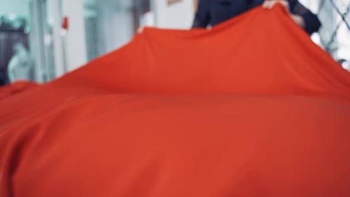 Woman Arranging Vibrant Red Fabric on Table