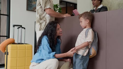 Mom Talking to Son while Father Talking to Receptionist at Hotel
