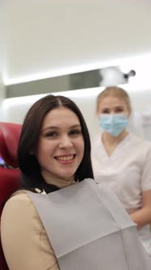 Fröhlicher Patient, der während eines Zahnarzttermins mit fürsorglichem Zahnarzt lächelt Vertikales Video