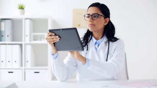 Female doctor browsing tablet computer in medical office at hospital