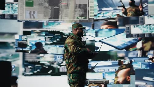 Soldier with Laptop Analyzing Data on Video Wall