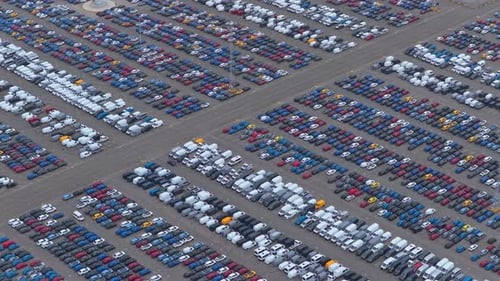 Rows of parked vehicles in shipping logistics terminal, aerial view