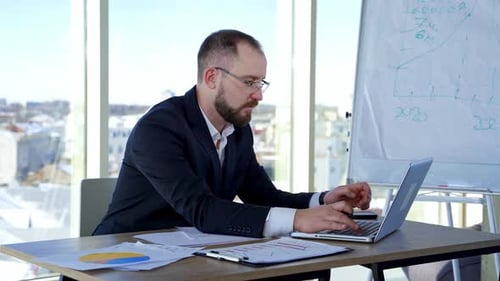 Serious male worker using laptop computer. Focused businessman working on laptop in office
