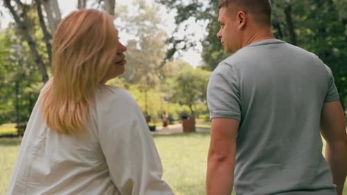 Porträt eines verliebten Paares, eines Mannes und einer schwangeren Frau, das Paar geht Händchen haltend durch den Park