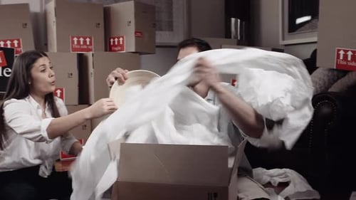 Couple Unpacking Belongings from Moving Boxes at Home