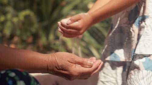 Granddaughter Pouring Sand Into Grandmother Hands in Park