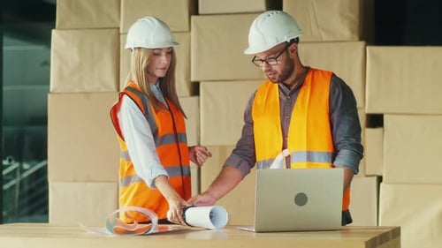 Ingenieure arbeiten mit Laptop und Bauplänen an einem Bauprojekt zusammen