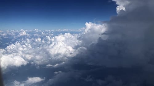 Aerial View of Cumulus Cloudscape From Airplane Window Against Blue Sky