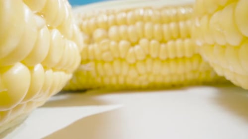 Sweet juicy corn. A few cobs are on the table. Summer, sunny day. Dolly slider extreme close-up. Lao