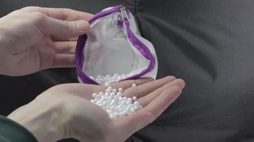 Hands Pouring White Beads Out of a Bag