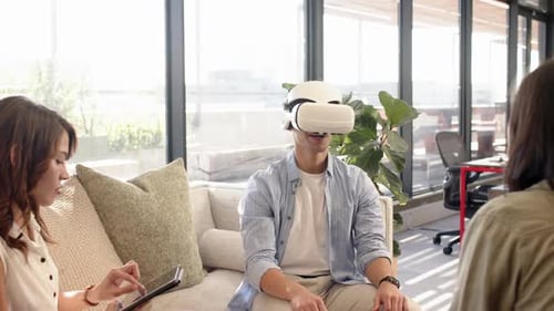 Vr headset, man exploring virtual interior design while multiracial colleagues watch, at office