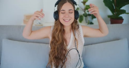 Cheerful Woman Enjoys Music with Headphones on Sofa